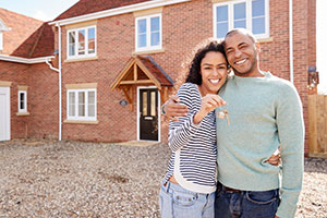Young Couple Holding Keys in front of New Home 