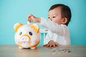 Child depositing a coin into a savings jar