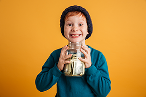 A young boy holding a saving jar